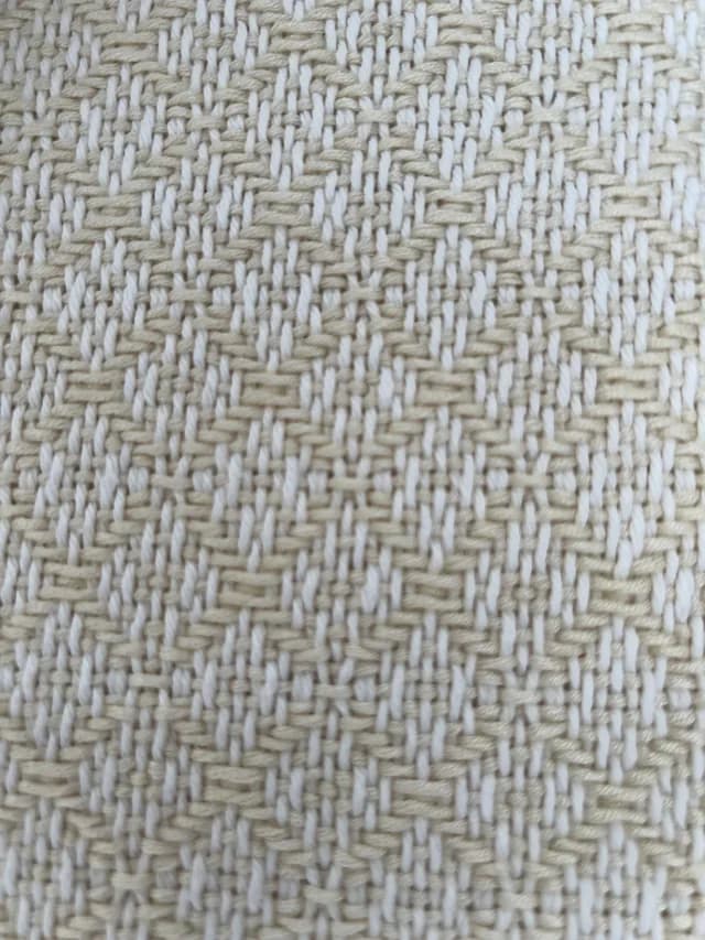 Gros plan sur le tissage géométrique serré en fil écru et blanc de la couverture