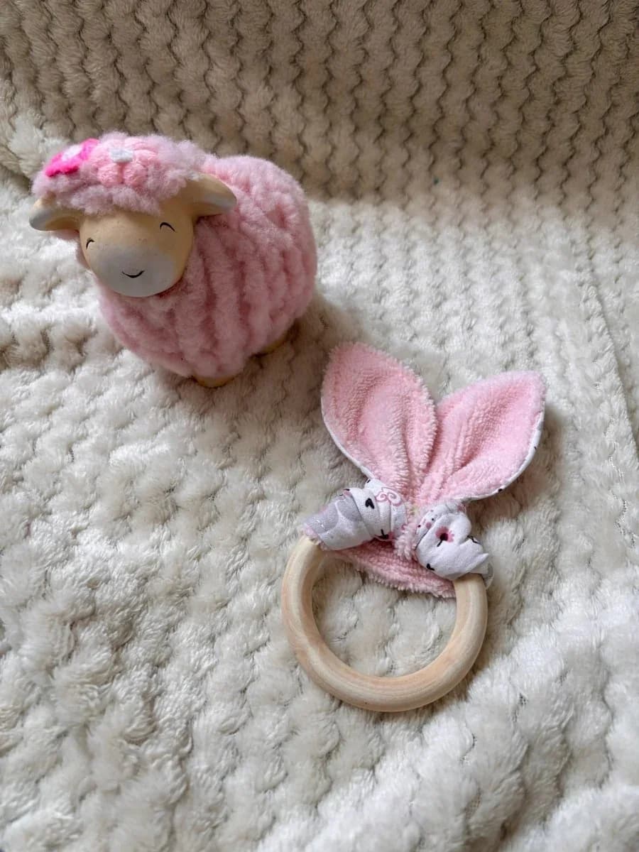 Anneau de dentition bébé en bois naturel orné d'un tissu rose poudré façon oreilles de lapin.