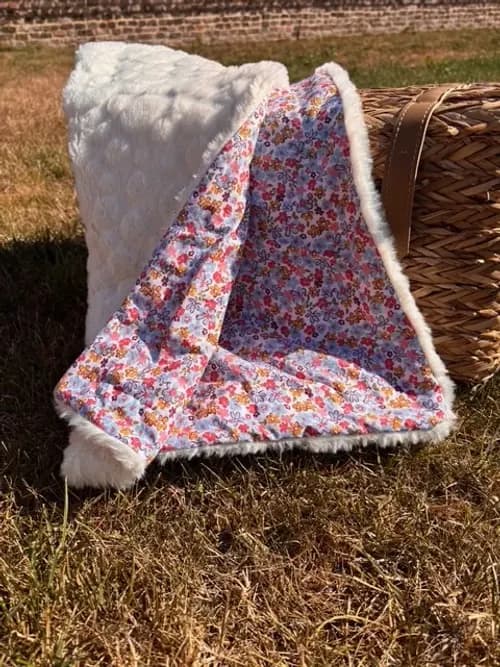 Couverture à petites fleurs multicolores suspendue aux barreaux d'un lit de bébé