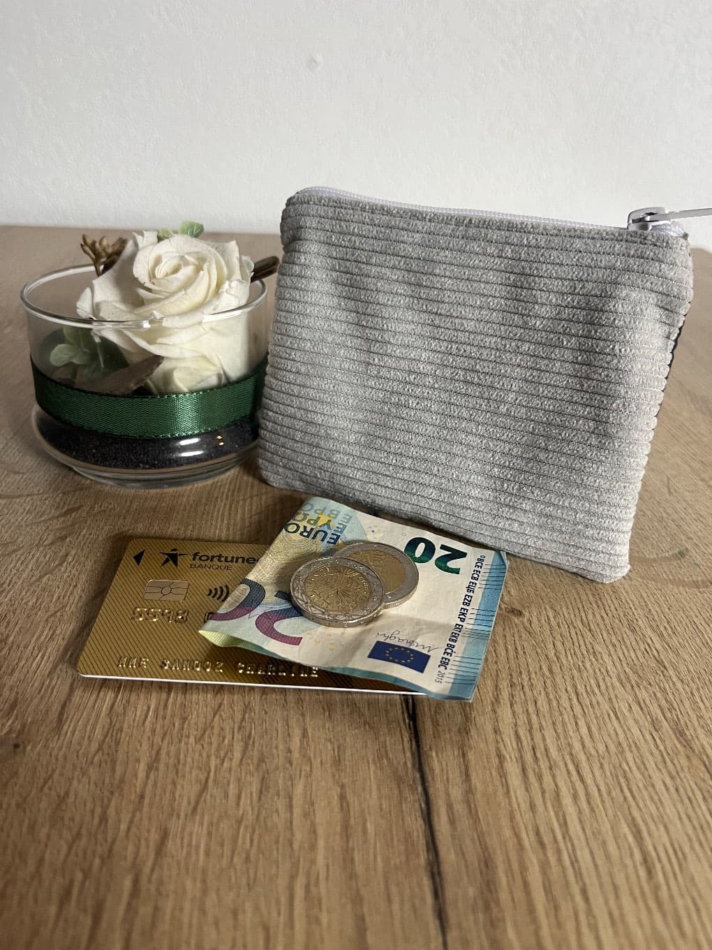Vue du dessus du porte-monnaie ouvert laissant voir la doublure imprimée et une carte bancaire.