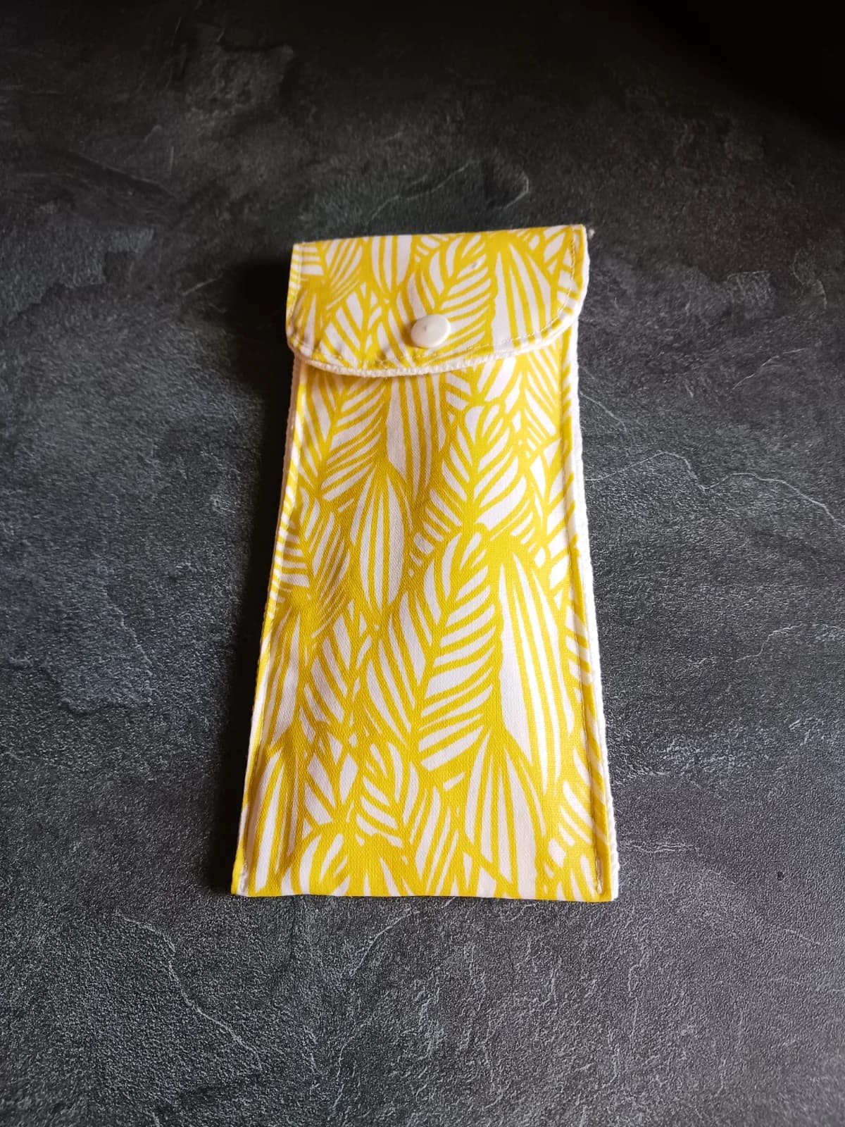 Étui à brosse à dents fermé à bouton-pression en tissu à motifs de feuillage jaune et blanc.